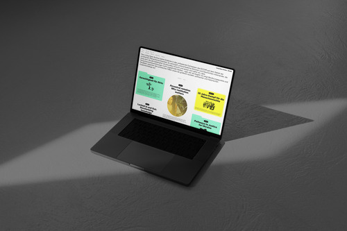 A laptop on the ground, with a website open that has items in turquoise and yellow over a white background.